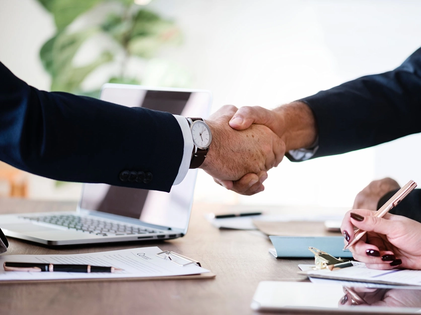 Two people shaking hands over a table